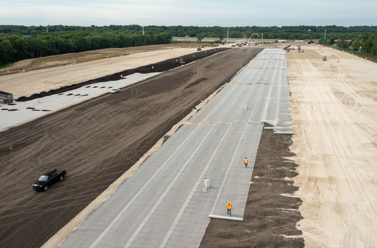 Geogrid being unrolled at a job site. Aggregate material is visible where grid being unrolled.